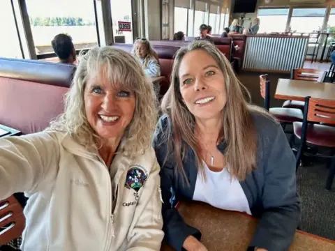 Two women smiling for a selfie in a restaurant