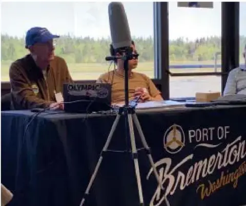 Two men at a presentation table with a projector and a Port of Bremerton banner
