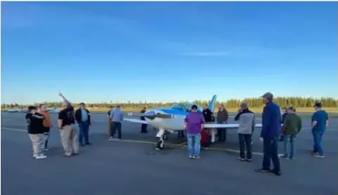People gathered around a low-wing airplane on the ramp at sunset