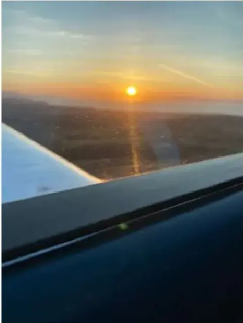 Sunset seen from the cockpit over the wing of a small airplane