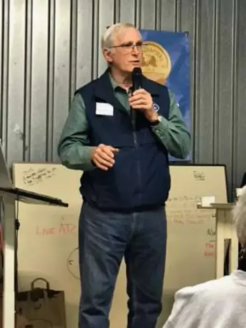 Man speaking into a microphone in a hangar