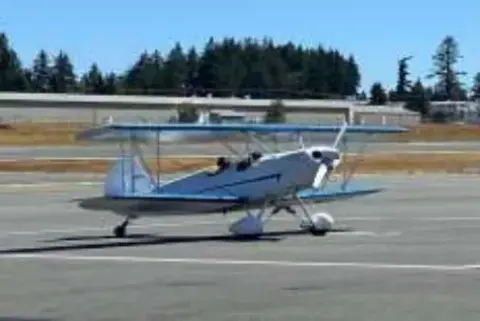 Blue and white biplane taxiing on the ramp