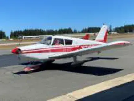 Red and white low-wing airplane parked on the ramp