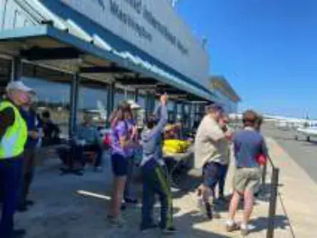 People standing by an airport terminal on a sunny day