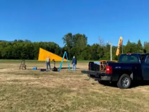 Orange tetrahedron on the airfield with a pickup truck parked nearby