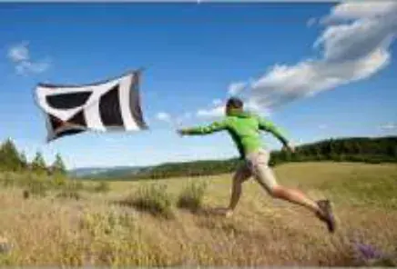 Man leaping across a meadow chasing a tent blowing in the wind