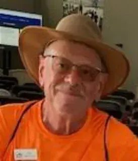 A smiling man in a cowboy hat and orange shirt