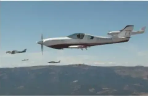 Red and white race plane flying in formation over hills