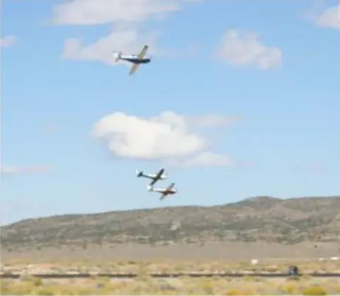 Race planes flying over a desert ridge
