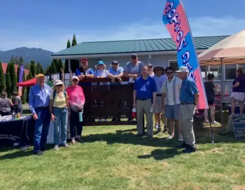 Fly-in crowd gathered by a hangar with a flag banner