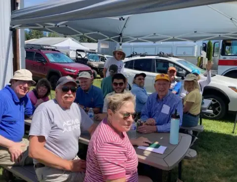 Fly-out group seated at tables under a canopy