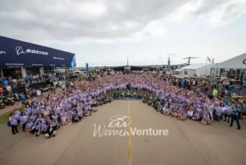 Large group of women in purple shirts posing for a group photo at AirVenture