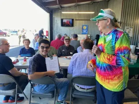 Poker game host in a tie-dye shirt walking between tables