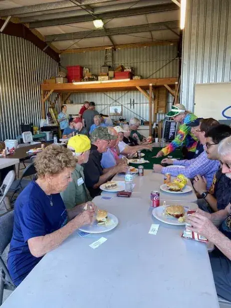 Poker game players eating at long tables in a hangar