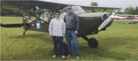 Two men standing in front of a Super Cub on the grass