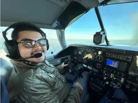 Young pilot in headset at the controls looking at the instrument panel