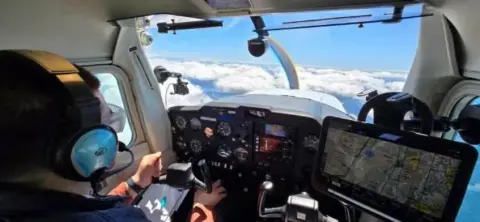 View over the shoulder of a pilot at a glass cockpit panel in flight