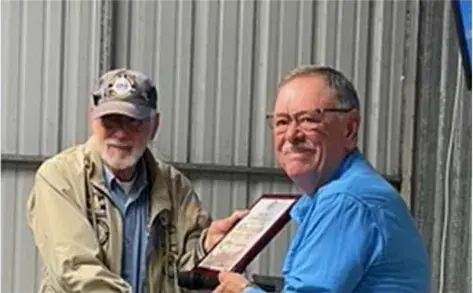 Man presenting a framed award to a smiling recipient