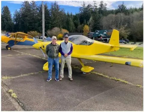 Two pilots beside a yellow Zenith-style airplane on the ramp