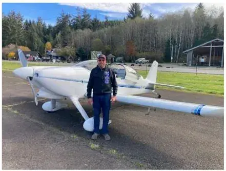 Pilot standing in front of a white low-wing airplane