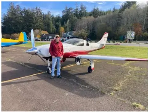 Pilot standing beside a red and white Lancair on the ramp
