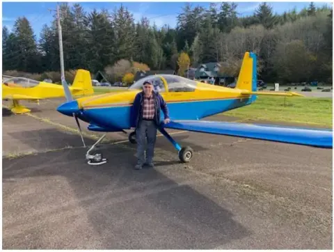 Pilot standing beside a blue and yellow RV on the ramp