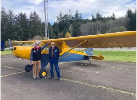 Two pilots beside a yellow Cub on the ramp
