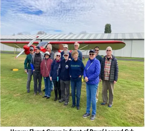 Fly-out group standing in front of a yellow Legend Cub