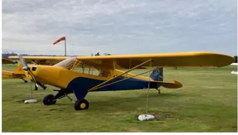 Yellow PA-11 Cub parked on the grass