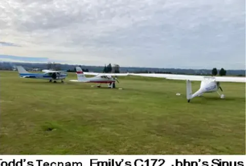 Three light airplanes parked on the grass at Harvey Field