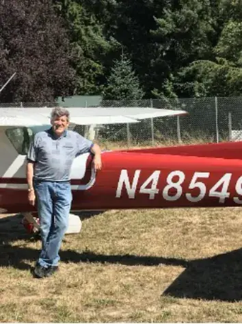 Man standing beside a red and white airplane, registration N4953M