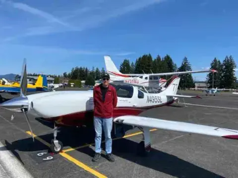 Pilot standing in front of a white low-wing airplane