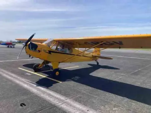 Yellow Cub-type airplane taxiing on the ramp