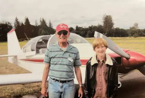 Older man and a young woman standing in front of a small airplane