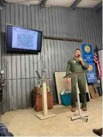 Presenter standing beside a screen in a hangar