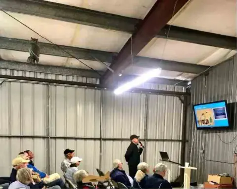 Speaker at the front of a hangar presentation with a screen