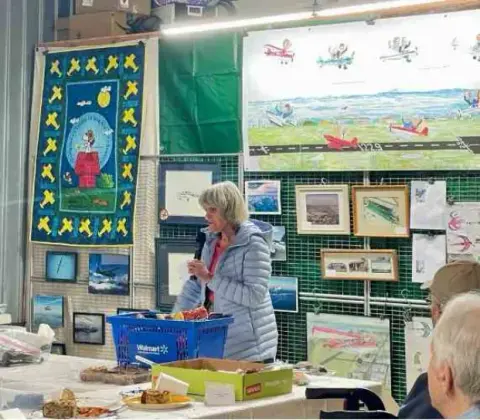 Woman presenting her aviation artwork at a display table