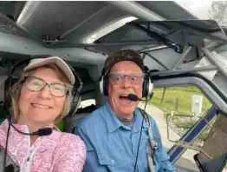 Pilot and passenger in headsets smiling in the cockpit