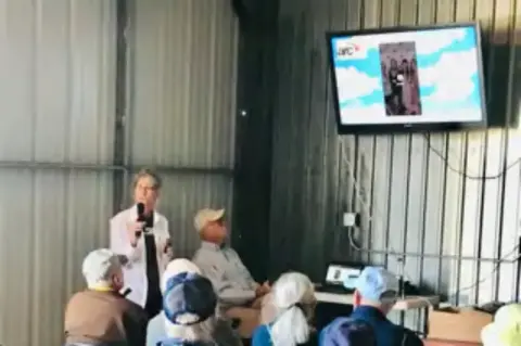 Members watching a presentation on a screen in a hangar