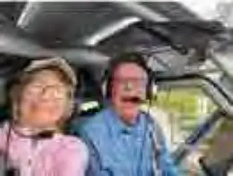 Two people in headsets smiling in a cockpit