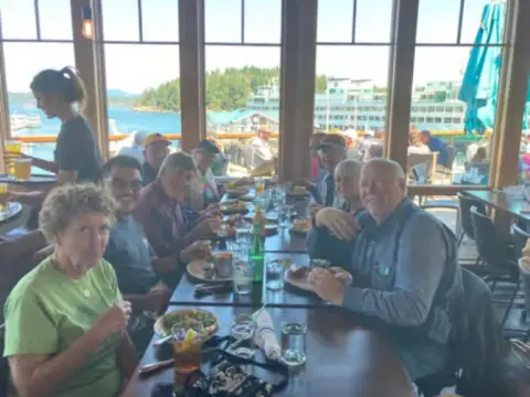 July fly-out group at a restaurant table by the windows