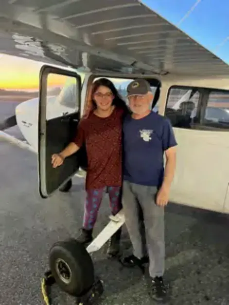 Young woman and a man standing at the door of a high-wing airplane