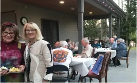 Board members and spouses at a dinner on a covered patio