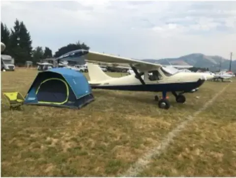 Camping tent beside a white airplane on a grass airfield