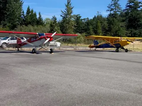 Several airplanes parked on the grass at Orcas Island