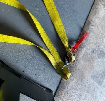 A yellow strap with a red handle on a hangar floor