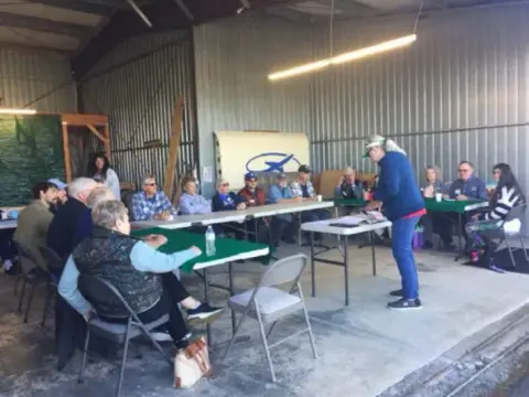 Poker Run players seated at card tables in the hangar
