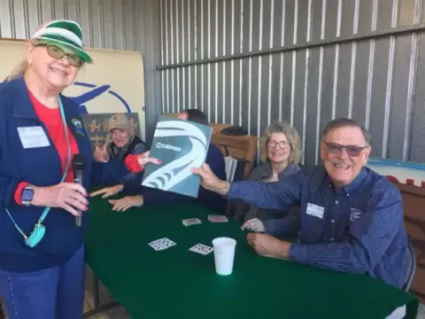Members laughing around a green card table during the Poker Run