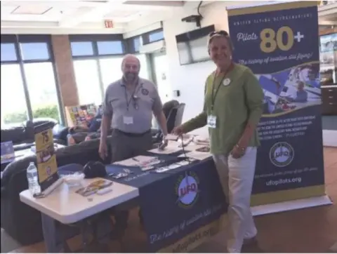 Two men at an information table at a trade show