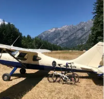 White high-wing airplane parked with mountains in the background